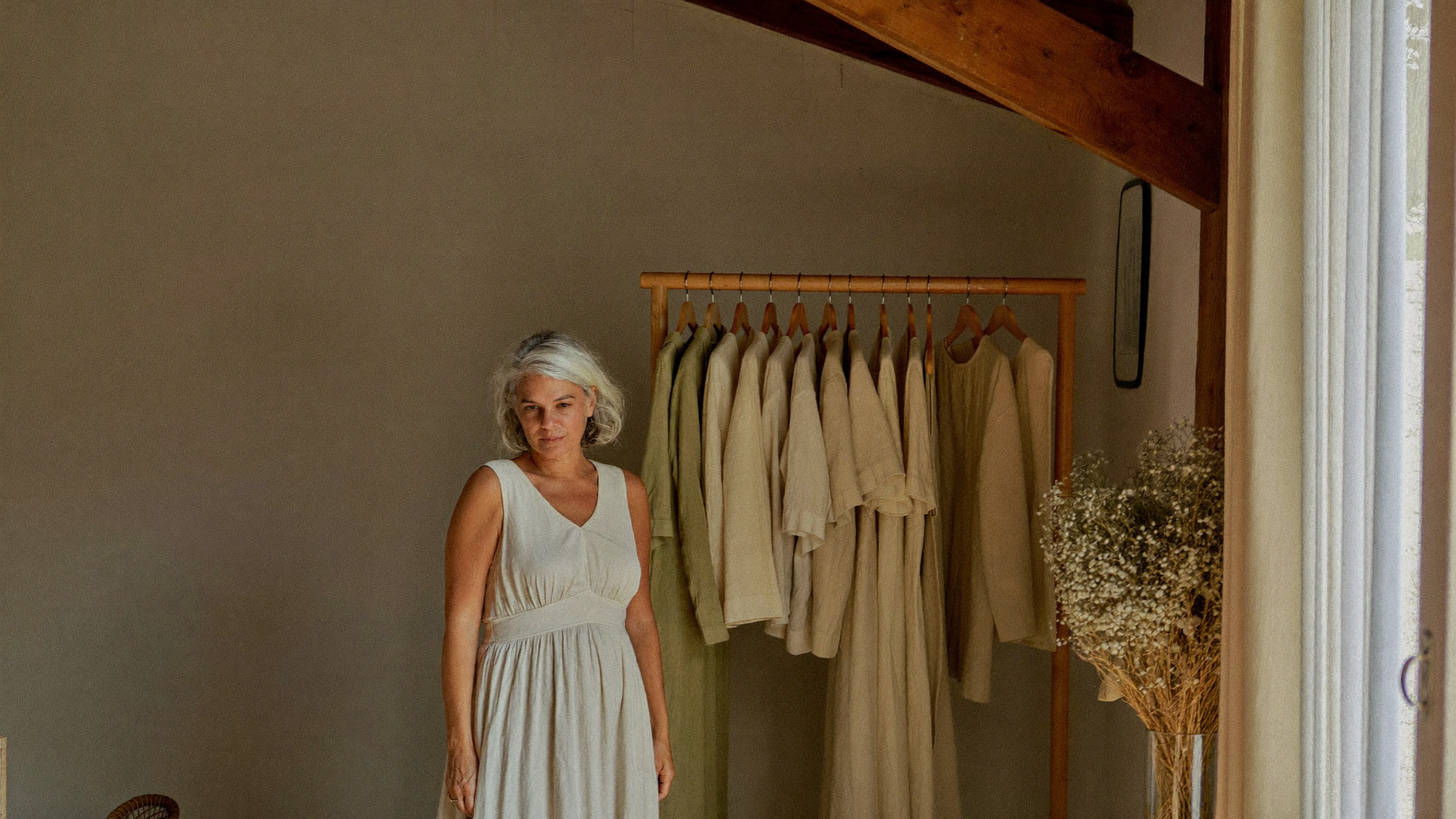 Frau in einem leichten Sommerkleid aus cremefarbenem Leinen in einer hellen Boutique